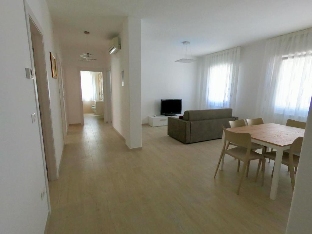 Zona giorno luminosa con tavolo, divano e cucina